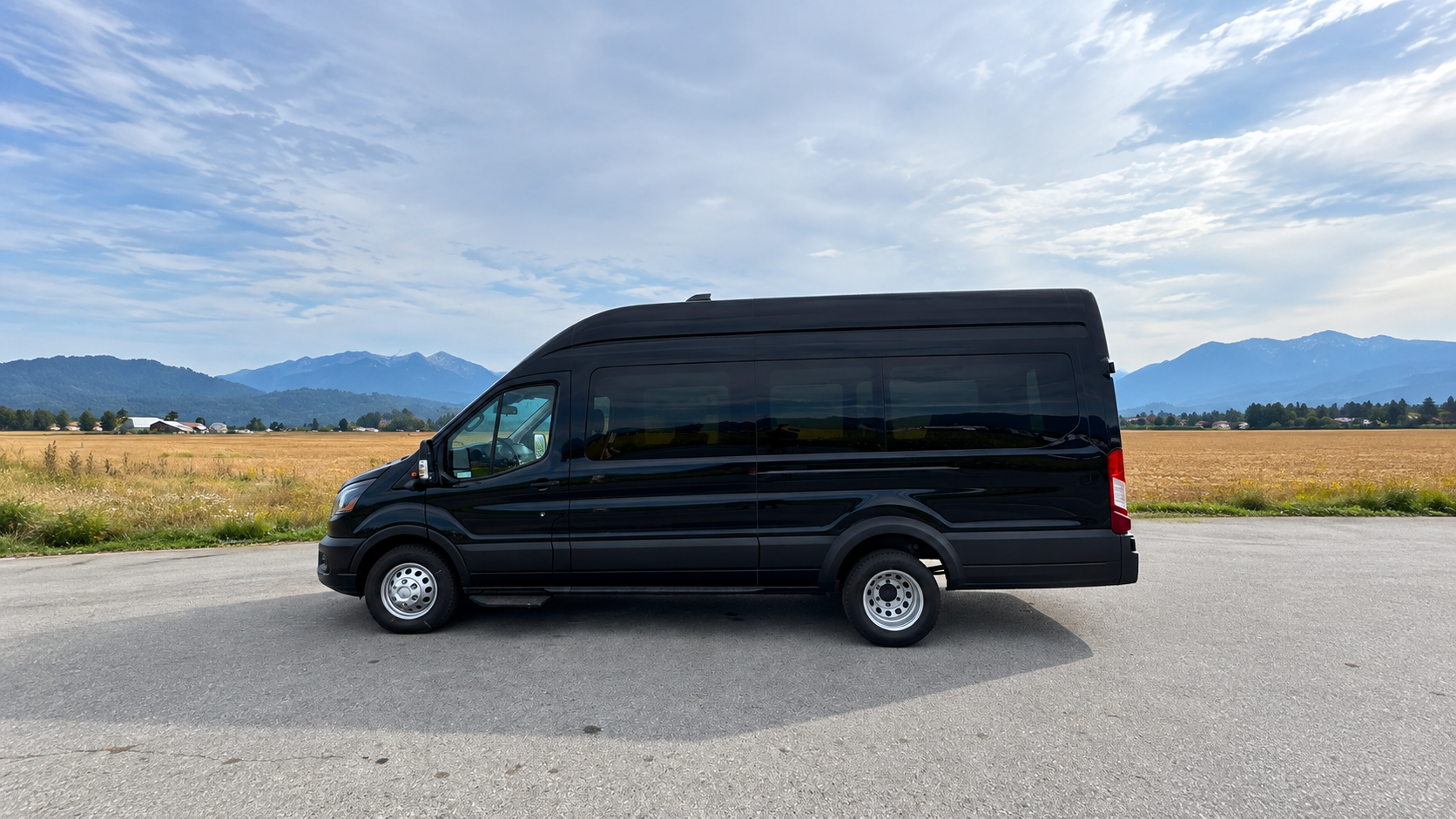 Black Ford Transit passenger van with the BC mountains behind