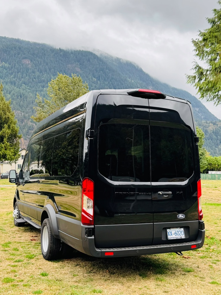 Black Ford Transit Wagon XLT 2026, rear view with misty BC mountains